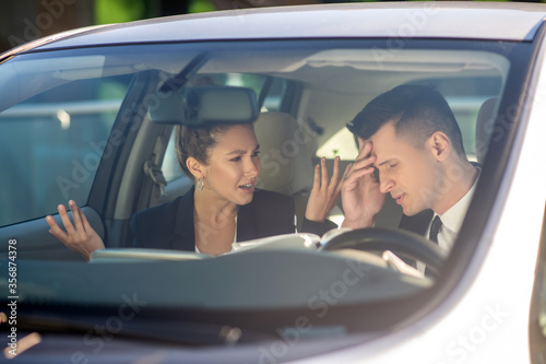 Business woman and man talking seriously in a car