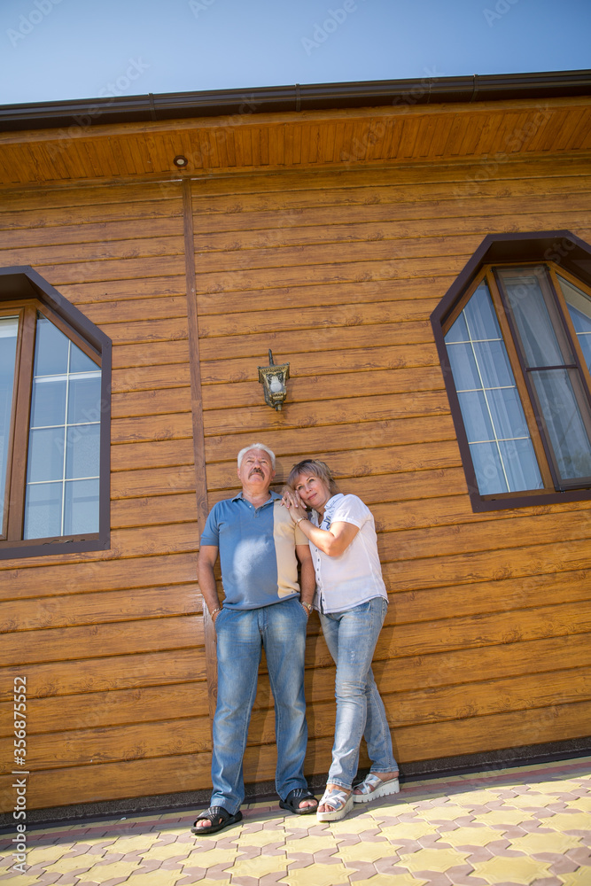 portrait of happy of middle aged couple against the background of house. Copy space