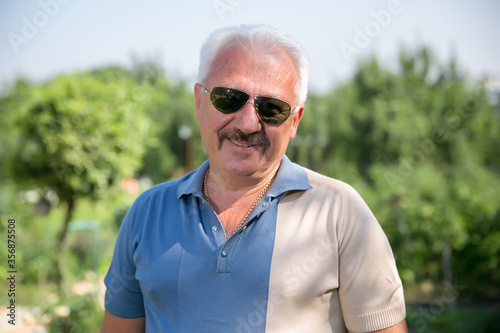 Senior grey-haired man in sunglasses in summer