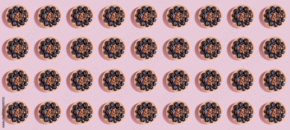 Pattern of tartlets with blueberries on a pink background with a shadow. Pattern of tartlets with blueberries on a pink background with a shadow.