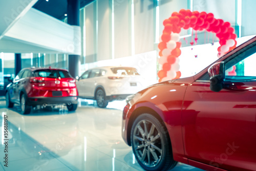 Blurred rear view of red and white luxury SUV car parked in modern showroom for sale. SUV car with sports design in showroom. Car dealership. Coronavirus impact on automotive industry concept.