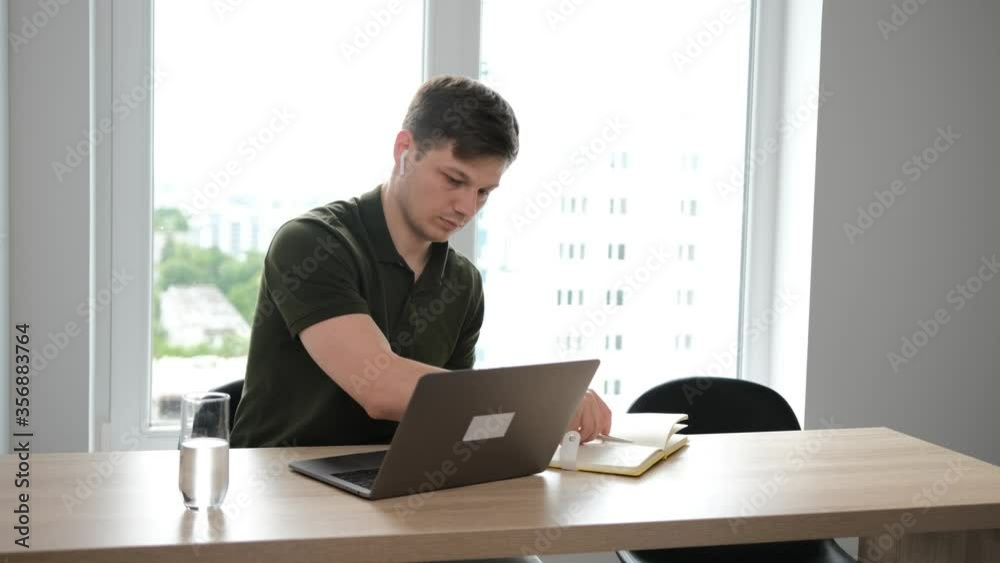 Young man working from home using the laptop, he notice the important things in the notebook. Stay at home and work from home concept Young man working from home using the laptop, he notice the important things in the notebook. Stay at home and work from home concept
