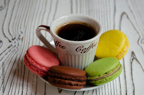 different macaroons on a white background with a cup of coffee