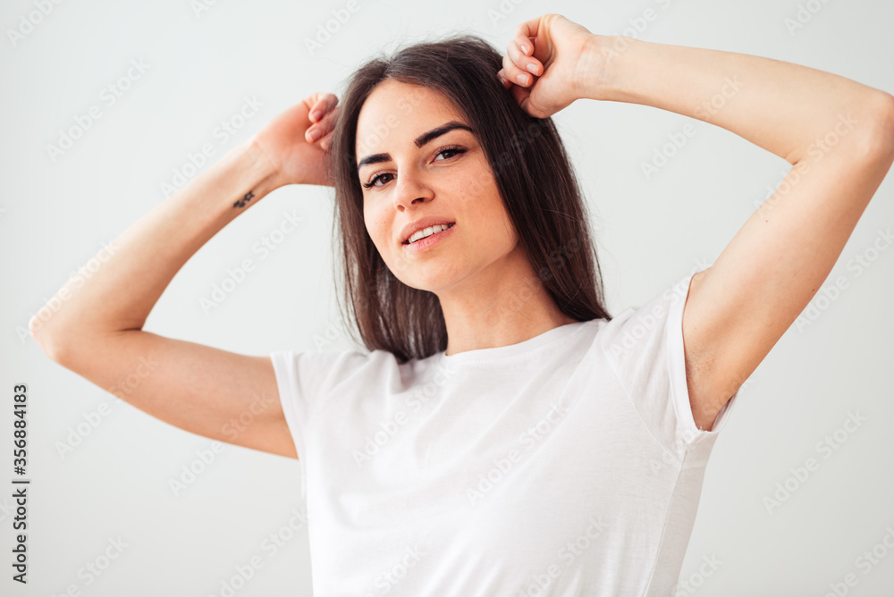 Gorgeous European woman smiling, keeping her hands behind your head. nice girl in a clean white t-shirt on a light background. Gorgeous European woman smiling, keeping her hands behind your head. nice girl in a clean white t-shirt on a light background.