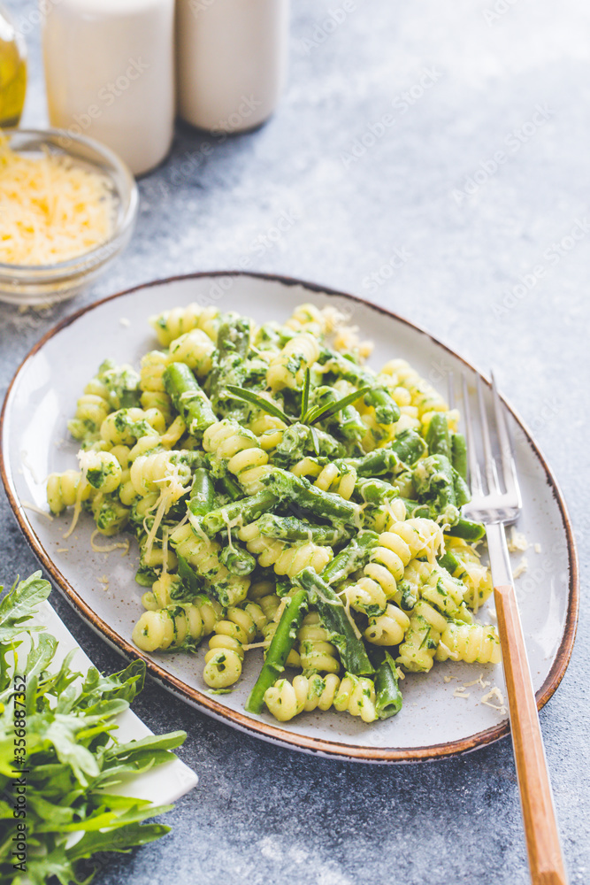 pasta with green vegetables and creamy sauce. fusilli pasta with asparagus beans and spinach on grey stone background pasta with green vegetables and creamy sauce. fusilli pasta with asparagus beans and spinach on grey stone background