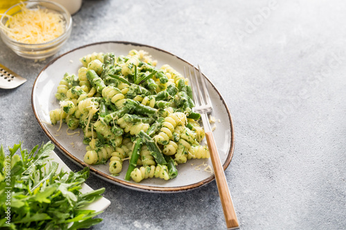 pasta with green vegetables and creamy sauce. fusilli pasta with asparagus beans and spinach on grey stone background