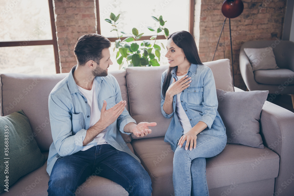 Portrait of positive cheerful spouses man woman have talk say tell incredible information secret rumor impressed touch hands chest sit couch in house indoors Portrait of positive cheerful spouses man woman have talk say tell incredible information secret rumor impressed touch hands chest sit couch in house indoors