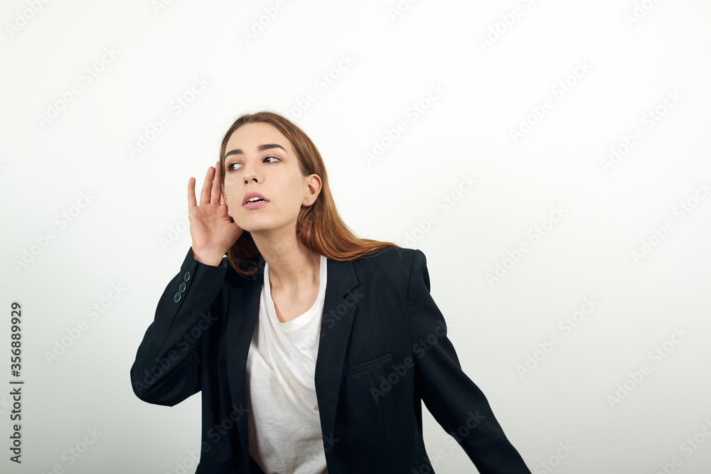 Eavesdropping, espionage, gossip, holding hand near head and looking away, what, relying on hand-ear listening the good news, trying to listen, cupping her ear. young attractive woman with brown hair