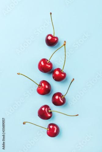 Composition of ripe cherries on a blue background. Flat lay, top view.