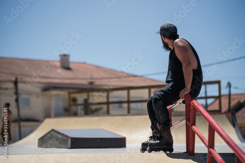 Inline skater siting on a skatepark checking the spots