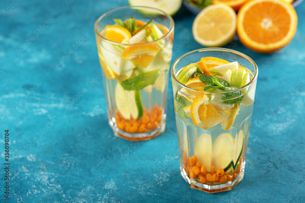 homemade lemonade with lemon, orange, sea buckthorn and mint in glasses on blue background