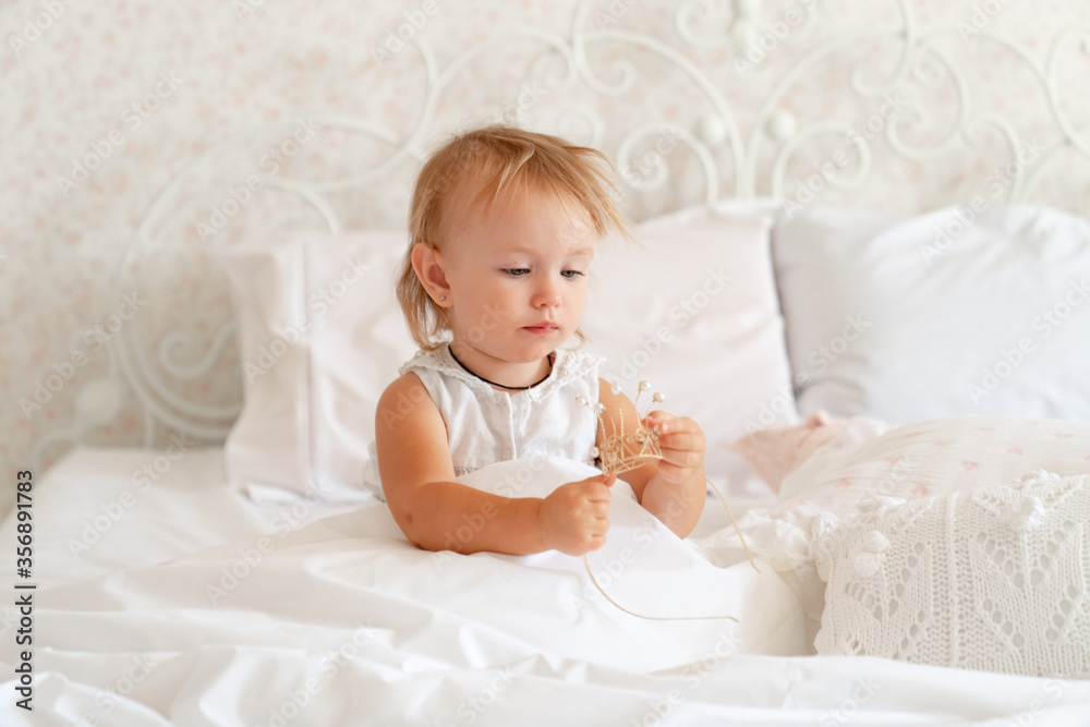 little girl sitting in bed in bedroom with crown. Princess birthday party. little girl sitting in bed in bedroom with crown. Princess birthday party.