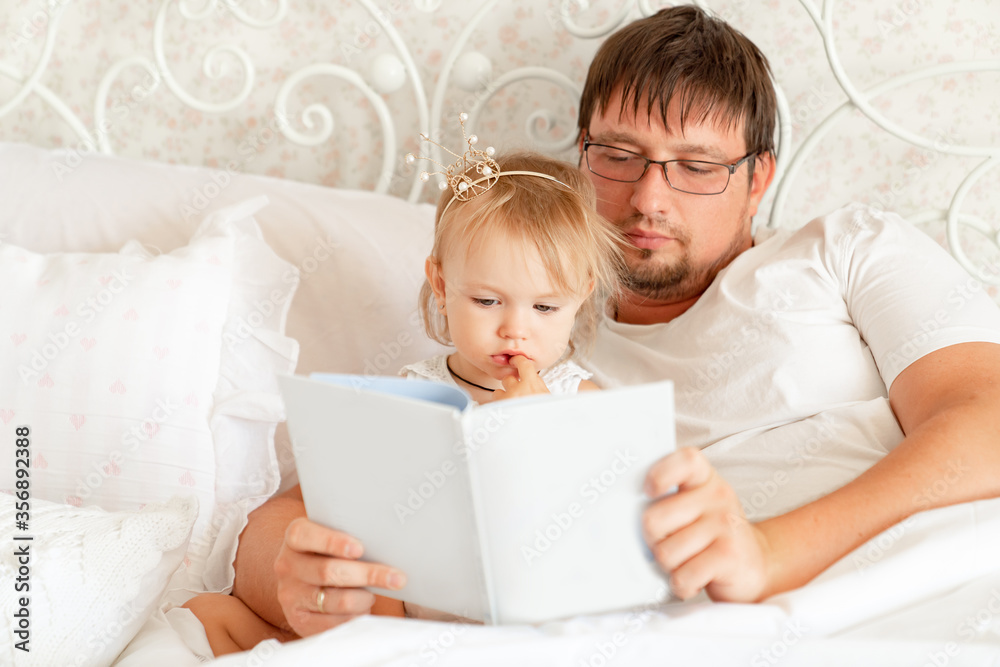 parents reading book to daughter in bed. place for text on white paper. parents reading book to daughter in bed. place for text on white paper.