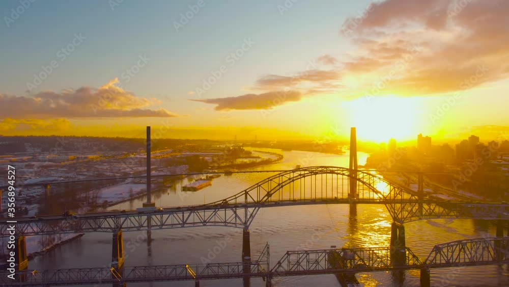Aerial Panoramic View of the Modern City, Bridge and Fraser River during a colorful Sunset. Taken in New Westminster, Vancouver, British Columbia, Canada. Aerial Panoramic View of the Modern City, Bridge and Fraser River during a colorful Sunset. Taken in New Westminster, Vancouver, British Columbia, Canada.