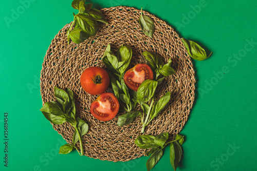 basil and tomatoes on a palm petate with a green background photo