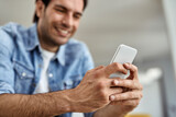Close-up of a man text messaging on cell phone at home.