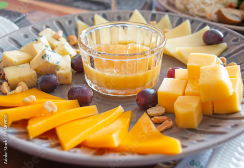 assorted cheese with grapes, sauce and peanuts, closeup photo