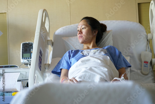 Asian chinese woman patient lying in hospital ward and looking out of the window