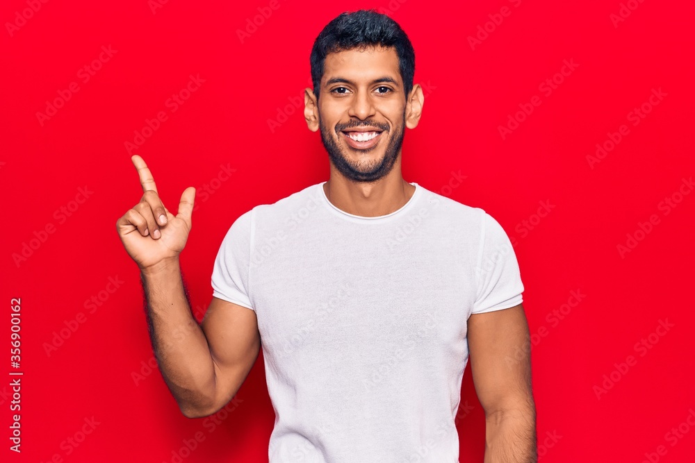 Young latin man wearing casual clothes smiling happy pointing with hand and finger to the side - obrazy, fototapety, plakaty 