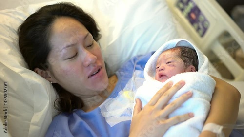 Asian Chinese Mother lying on hospital bed and carrying her newborn