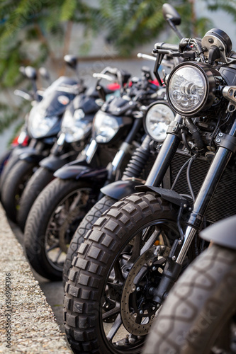 Vertical close-up detail of brand-new motorcycles parked in a row, in a motorbike dealership. Several bikes for sale