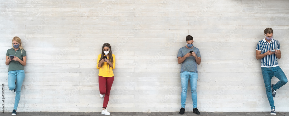Young people wearing surgical mask using mobile phone keeping social distance - Millennial friends watching media trends on smartphones during corona virus outbreak - Youth and technology concept - obrazy, fototapety, plakaty 