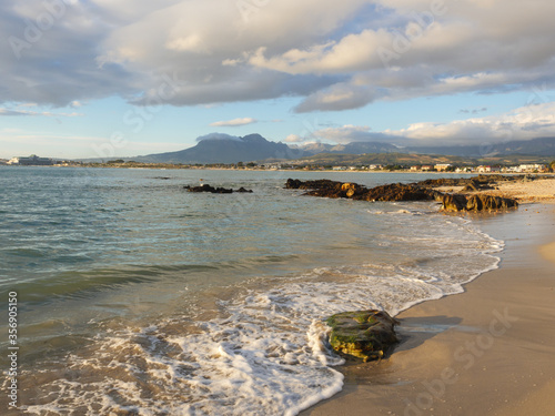 Photography A single wave rushes up the sandy beach to splash over a small rock
