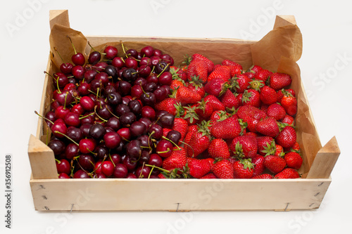 fresh strawberries and cherries in a wooden box on a white background
