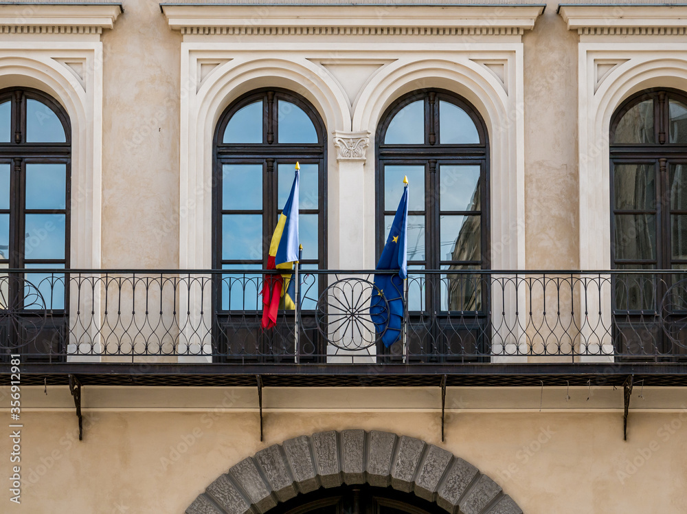 Architectural detail of a institution building in Bucharest. Romanian an European Union flags on a balcony in Romania.