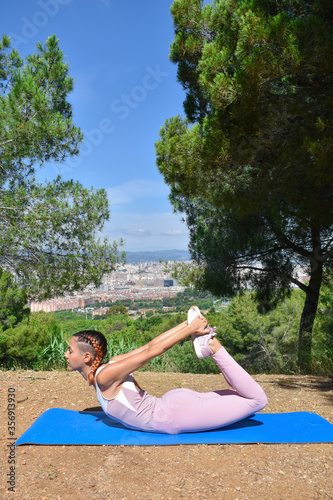 Woman doing yoga and pilates poses to clear mind and stretch muscles in the park