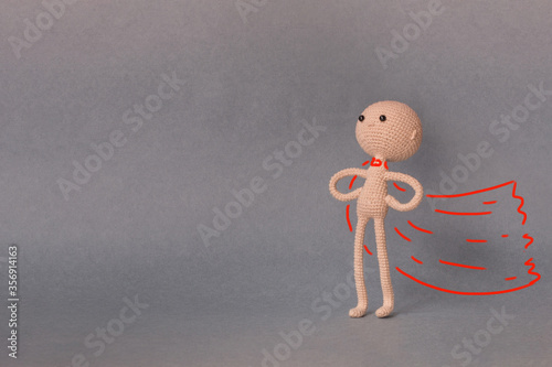 A toy man on a gray background with copy space. Presentation PowerPoint or Keynote. Motivational phrase. A sketch is drawn on top of the photo.Man with red cloak in the pose of a superhero