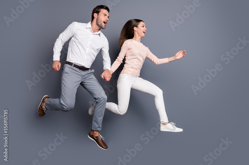 Full body profile photo pretty lady handsome guy couple hold hands good mood running shopping center mall together addicted shoppers wear shirts pants shoes isolated grey color background