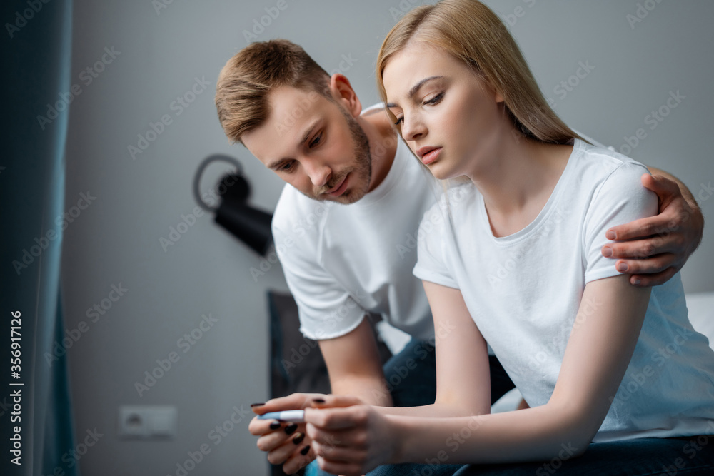 sad man and frustrated girlfriend looking at pregnancy test at home sad man and frustrated girlfriend looking at pregnancy test at home
