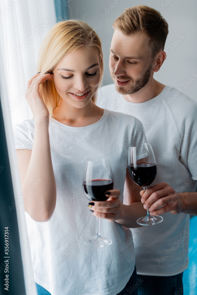 handsome man looking at woman and holding glass with red wine handsome man looking at woman and holding glass with red wine