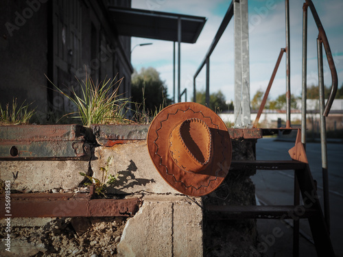 Alte rostige Beton Stiege mit einem Cowboyhut und ein verlassenes Gebäude im Hintergrund, Vintage Stil, Einsamkeit photo