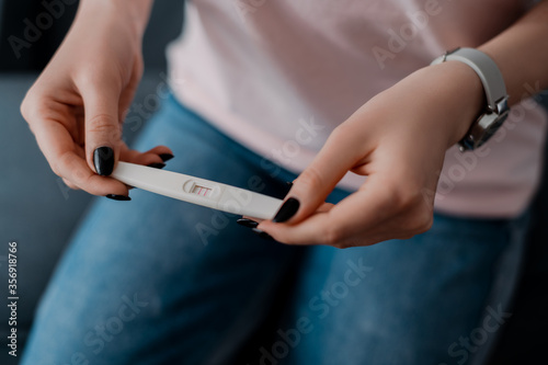 cropped view of girl holding pregnancy test with positive result © LIGHTFIELD STUDIOS