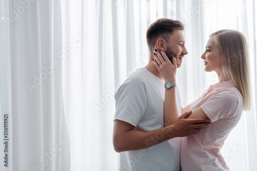 side view of girl with engagement ring on finger touching face of handsome man