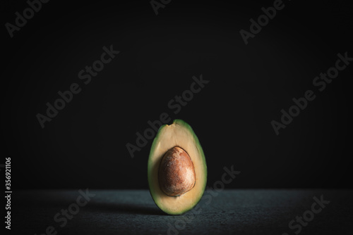 Halved avocado on black background with space for your text