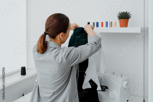 Young woman tailor is arranging a future shirt on a mannequin in her mini workshop. photo