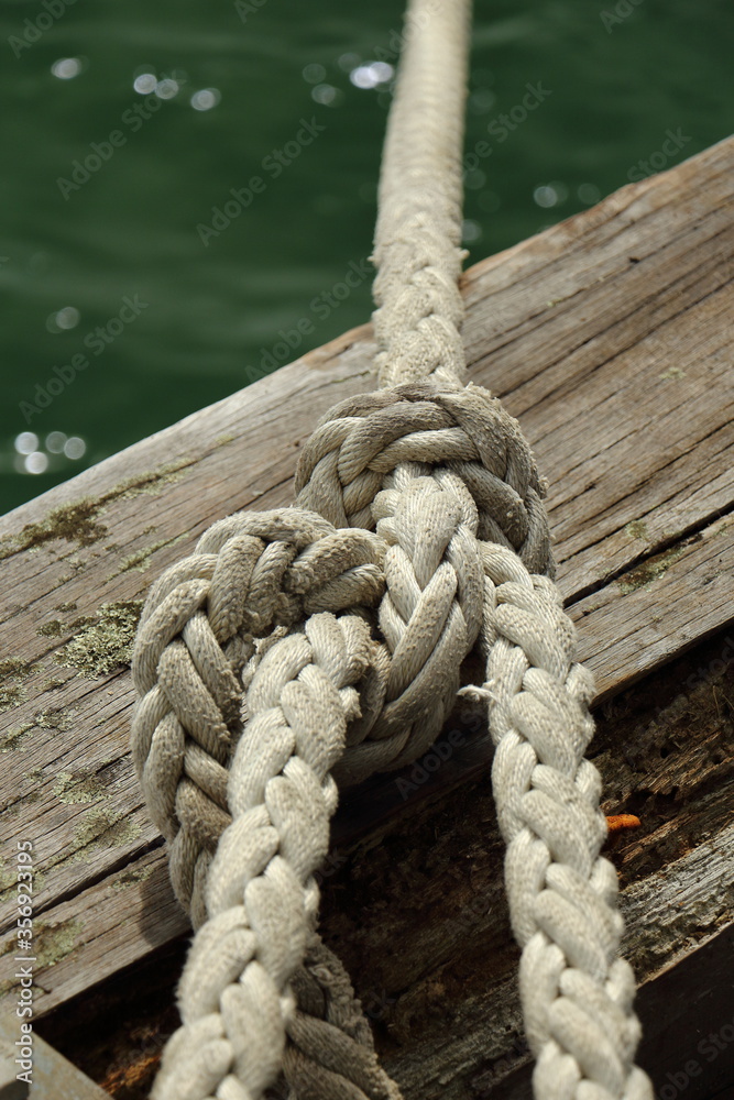 Close up of knotted mooring rope on wooden wharf