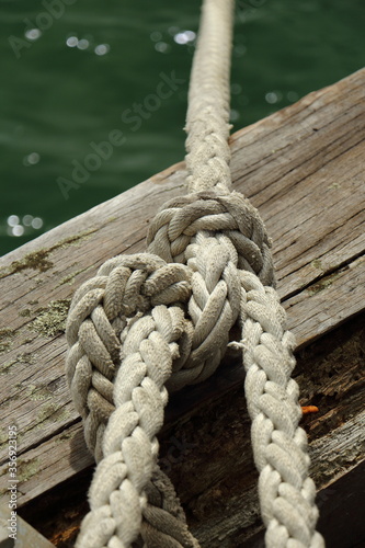Close up of knotted mooring rope on wooden wharf © Simon