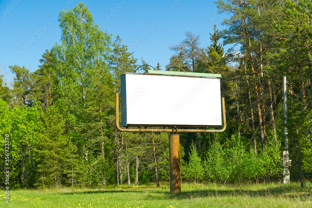 white billboard on a background of green forest. suitable for advertising. Blank billboard and outdoor advertising. white Mockup poster outside in forest.