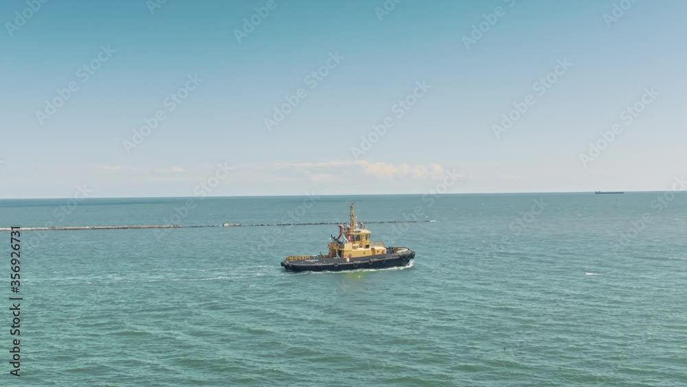Aerial drone video of yellow tugboat goes to a large cargo ship to transport to the dock. Cargo ship barge and tugboat sail to meet each other in the seaport of the port. Aerial View. Drone shoot. Aerial drone video of yellow tugboat goes to a large cargo ship to transport to the dock. Cargo ship barge and tugboat sail to meet each other in the seaport of the port. Aerial View. Drone shoot.