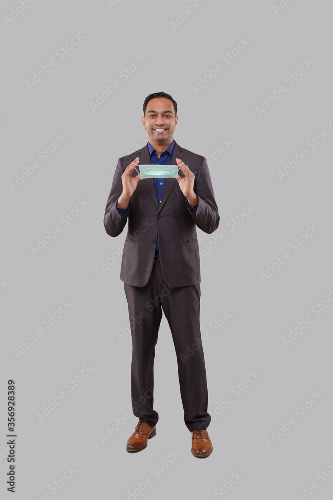 Businessman Puts on Medical Mask Isoalted. Indian Businessman Standing Full Length with Medical Mask in Hands Businessman Puts on Medical Mask Isoalted. Indian Businessman Standing Full Length with Medical Mask in Hands