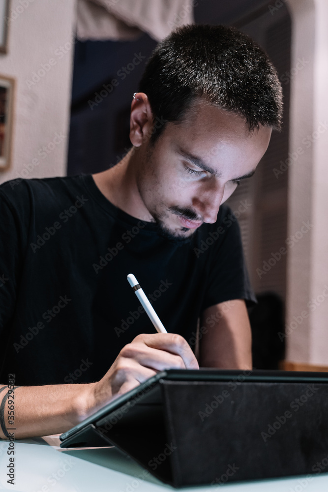 Vertical photo of a man with piercings using a tablet with a digital pen Vertical photo of a man with piercings using a tablet with a digital pen