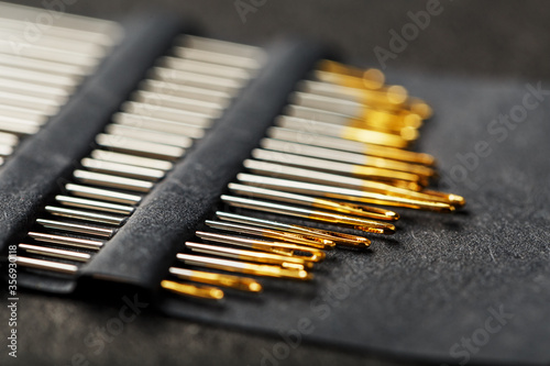 Set of Gold needles on a black background in a row.