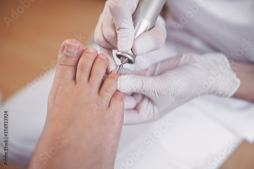 Hardware medical pedicure with nail file drill apparatus. Patient on pedicure treatment with pediatrician chiropodist. Foot peeling treatment at spa with a special device. Clinic of Podiatry Podology photo