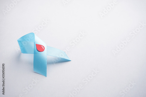 The blue ribbon with blood drop on a gray background, flat lay. World diabetes day, 14 november. Space for text. Diabetes concept.