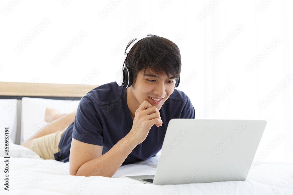 Happy man using Laptop computer and checking good News in the Bedroom. COPY SPACE. Trading. Watching Movie. WORK FROM HOME WFH Concept. Happy man using Laptop computer and checking good News in the Bedroom. COPY SPACE. Trading. Watching Movie. WORK FROM HOME WFH Concept.