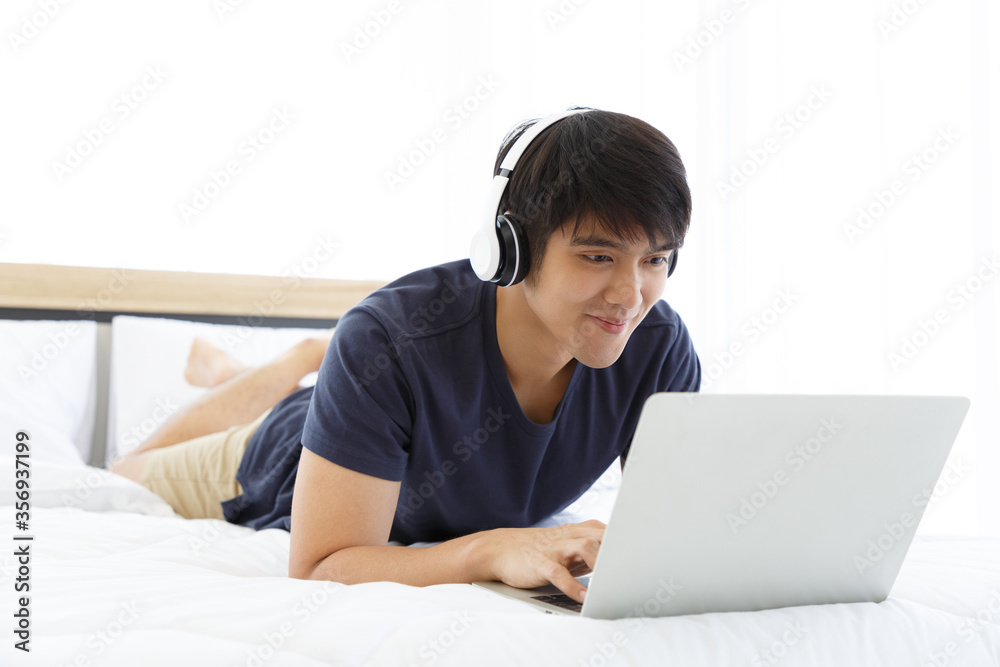 Happy man using Laptop computer and checking good News in the Bedroom. COPY SPACE. Trading. Watching Movie. WORK FROM HOME WFH Concept. Happy man using Laptop computer and checking good News in the Bedroom. COPY SPACE. Trading. Watching Movie. WORK FROM HOME WFH Concept.